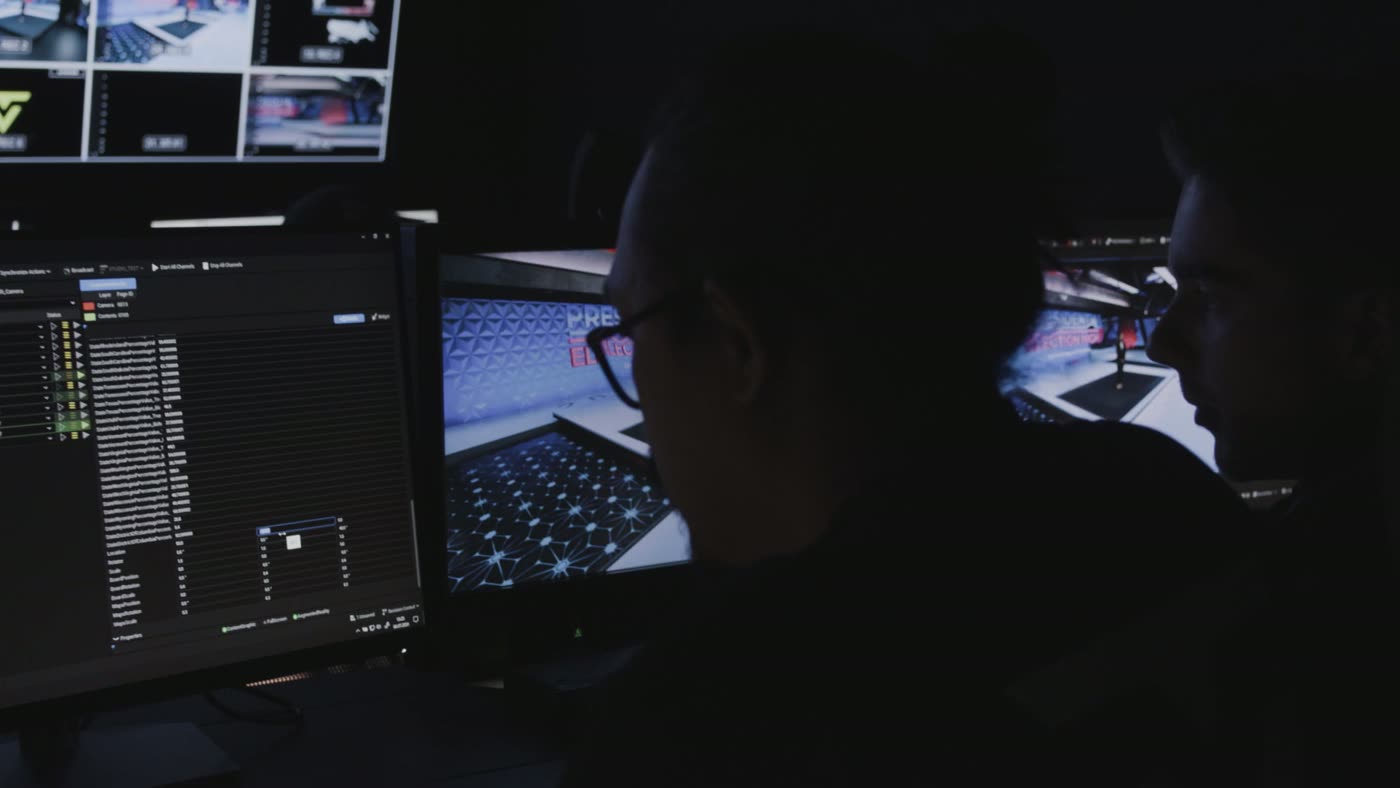 Gallery operator at a desk in front of a multiviewer wall